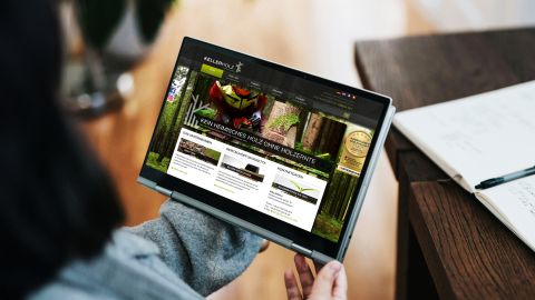 Person hält Tablet mit geöffneter Kellerholz-Website, die Informationen zur Holzernte und nachhaltiger Forstwirtschaft zeigt.