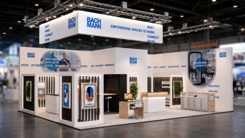 Messestand Bachmann mit Hängebanner "Empowering Spaces to Work" und Bildschirmen
