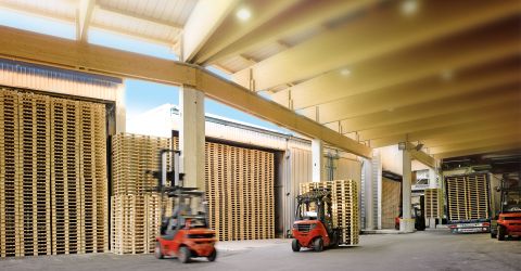 Palettenlager mit Gabelstaplern in Aktion Großes Palettenlager mit gestapelten Holzpaletten und mehreren Gabelstaplern im industriellen Betrieb.
