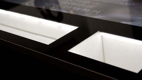 Detailansicht eines beleuchteten Präsentationsdisplays für Uhren mit schwarzem Rahmen und heller Innenbeleuchtung.