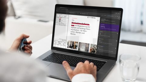 Mann arbeitet an einem Laptop mit geöffneter Website und Entwickler-Tools, auf einem Schreibtisch mit Glas Wasser.