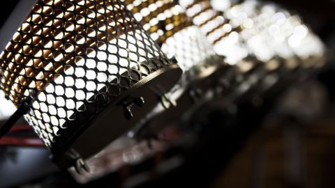 Nahaufnahme industrieller Strahler mit wabenförmigem Metallschutz und heller LED-Beleuchtung in dunkler Umgebung.