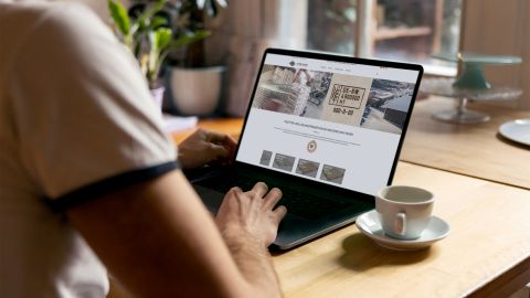 Treyer-Website auf Laptop Person nutzt Laptop mit geöffneter Treyer-Website, daneben eine Kaffeetasse auf einem Holztisch.