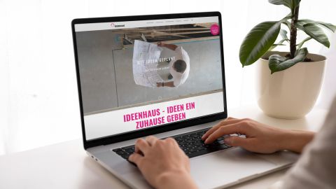 Person nutzt Laptop mit geöffneter Ideenhaus-Webseite und dem Slogan „Ideen ein Zuhause geben“.