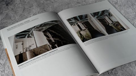 Doppelseite aus dem Bauen-Katalog von Jogerst zum Thema "Naturstein im Bad" mit Fotos und Texten über das Projekt einer edlen Herrentoilette mit hinterleuchteter Dünnglas-Wandverkleidung aus dunklem Naturstein.