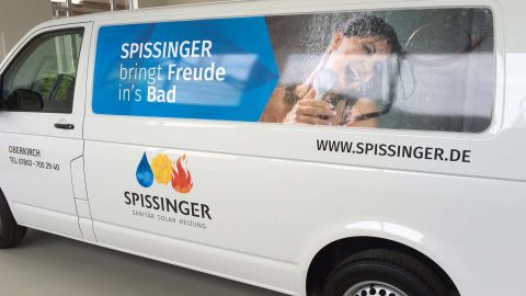 Werbefahrzeug von Spissinger mit Slogan „bringt Freude ins Bad“ und Bild einer singenden Frau unter der Dusche.