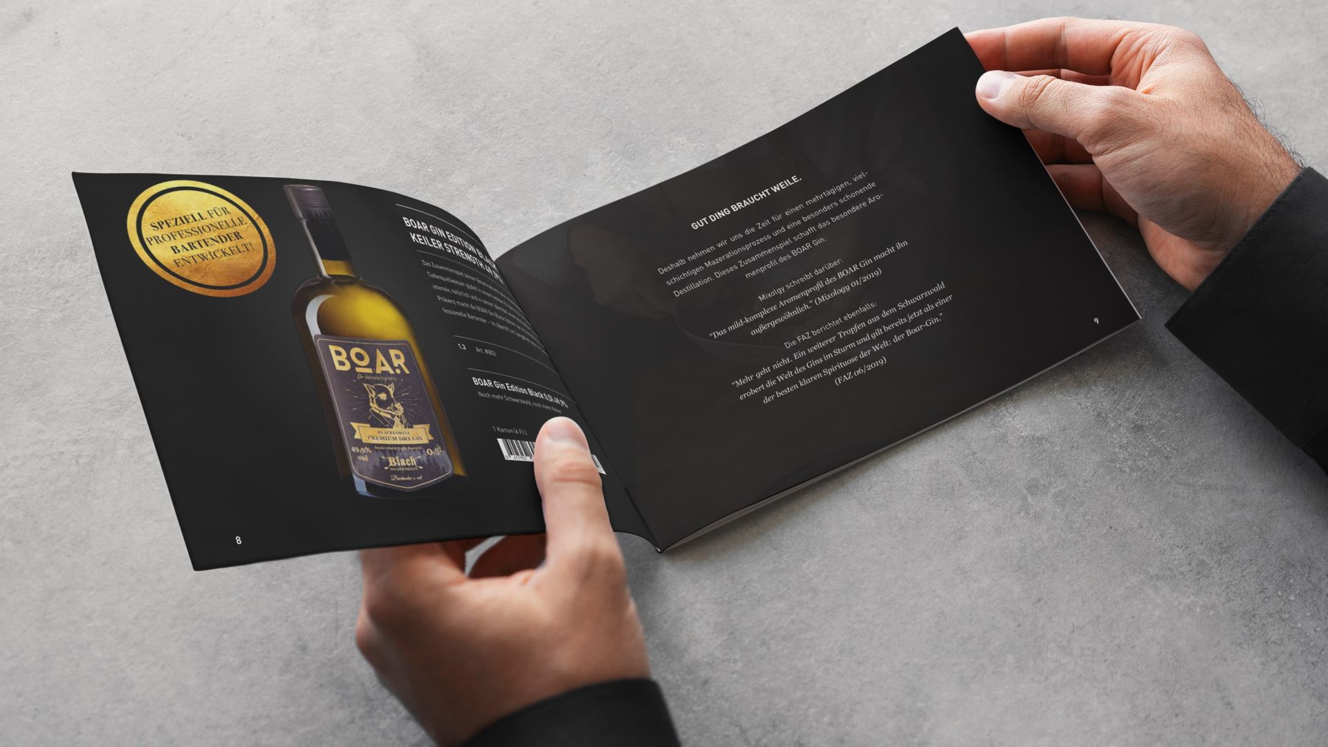 Zwei Hände halten eine aufgeschlagene Broschüre mit dem Produktsortiment von BOAR: auf schwarzem Hintergrund ist dort eine Flasche BOAR Black neben Text abgebildet.