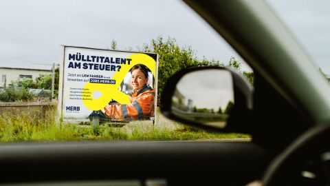 Reklameplakat mit Jobangebot für LKW-Fahrer von MERB am Straßenrad, aus dem Auto heraus fotografiert.