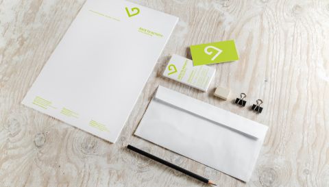 Geschäftsausstattung von Back to Activity mit Briefpapier, Visitenkarten, Umschlag und Schreibutensilien auf hellem Holztisch.