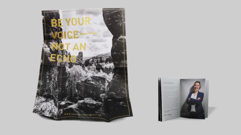 Gefaltetes Poster mit dem Schriftzug „Be your voice – not an echo“ neben einem aufgeschlagenen Magazin mit Portraitfoto einer Frau.